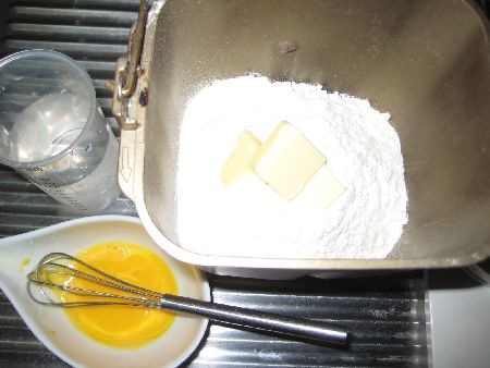 パンケースに計量した粉類に冷水、卵を加える画像